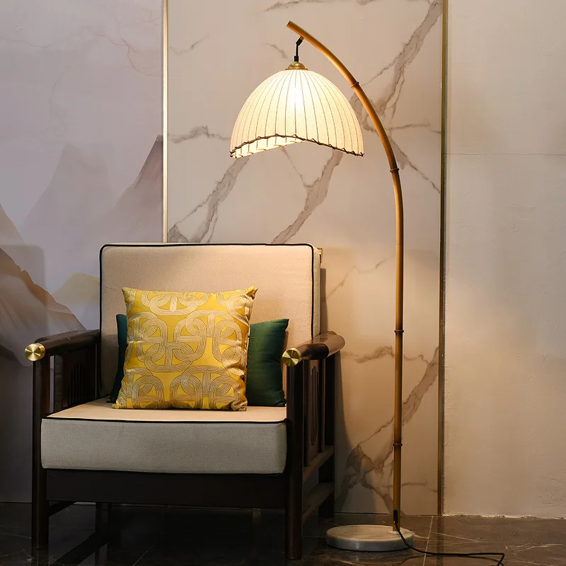 Lampadaire champignon LED au design nordique en bambou et toile sur fond blanc avec un fauteuil et un coussin à gauche