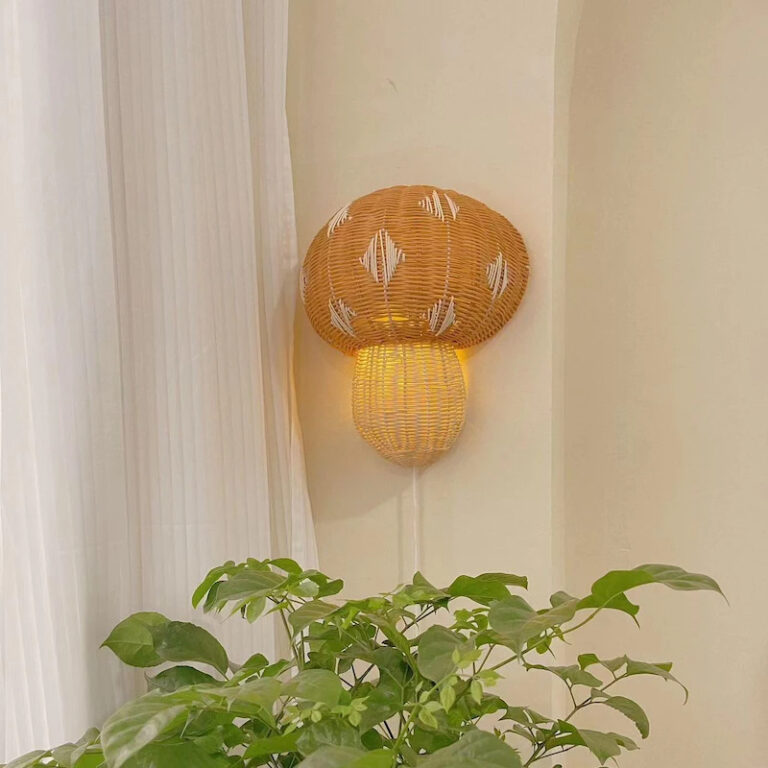 Lampe champignon bois murale en rotin faite à la main sur fond beige avec une plante verte en bas