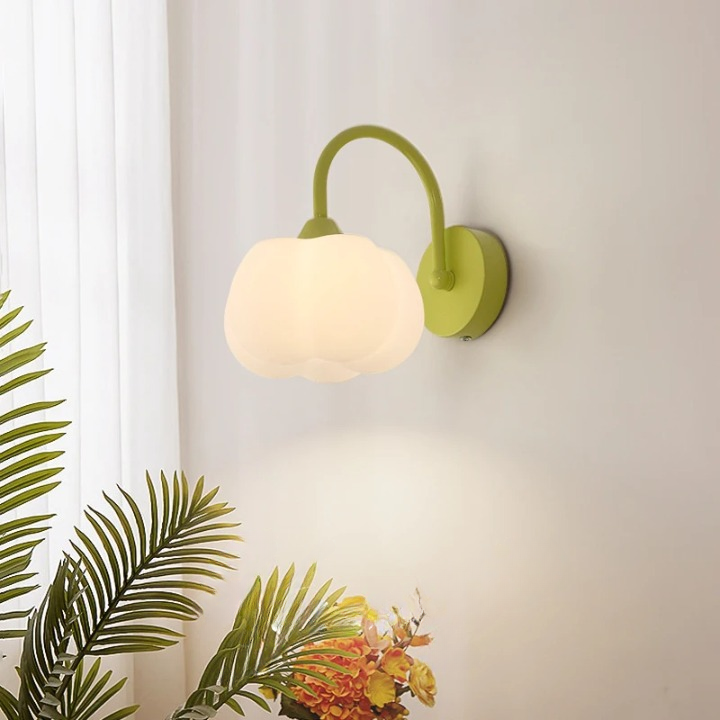 Lampe champignon murale blanche et verte sur fond gris avec des plantes à gauche