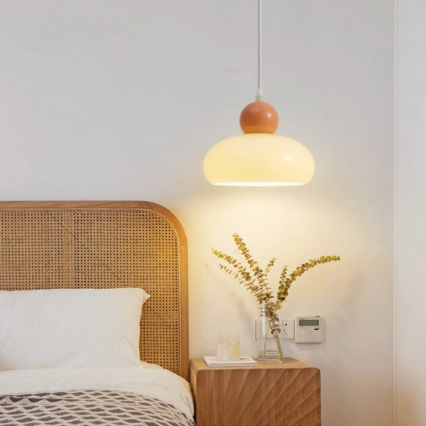 Suspension champignon beige LED en verre sur fond gris avec un lit une table de nuit et une plante