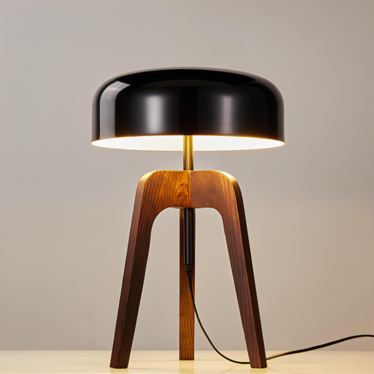 Lampe avec trépied en bois et abat-jour noir en métal. Lampe allumée sur fond gris.