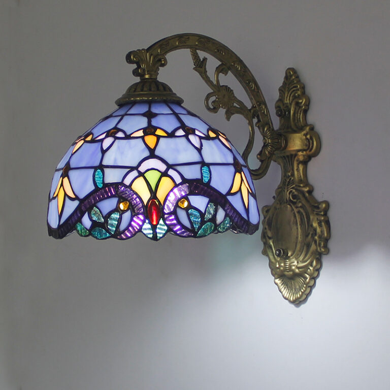 Lampe champignon dans le style tiffany aux tons bleus. Son support mural est de style baroque doré. La lampe est allumée.