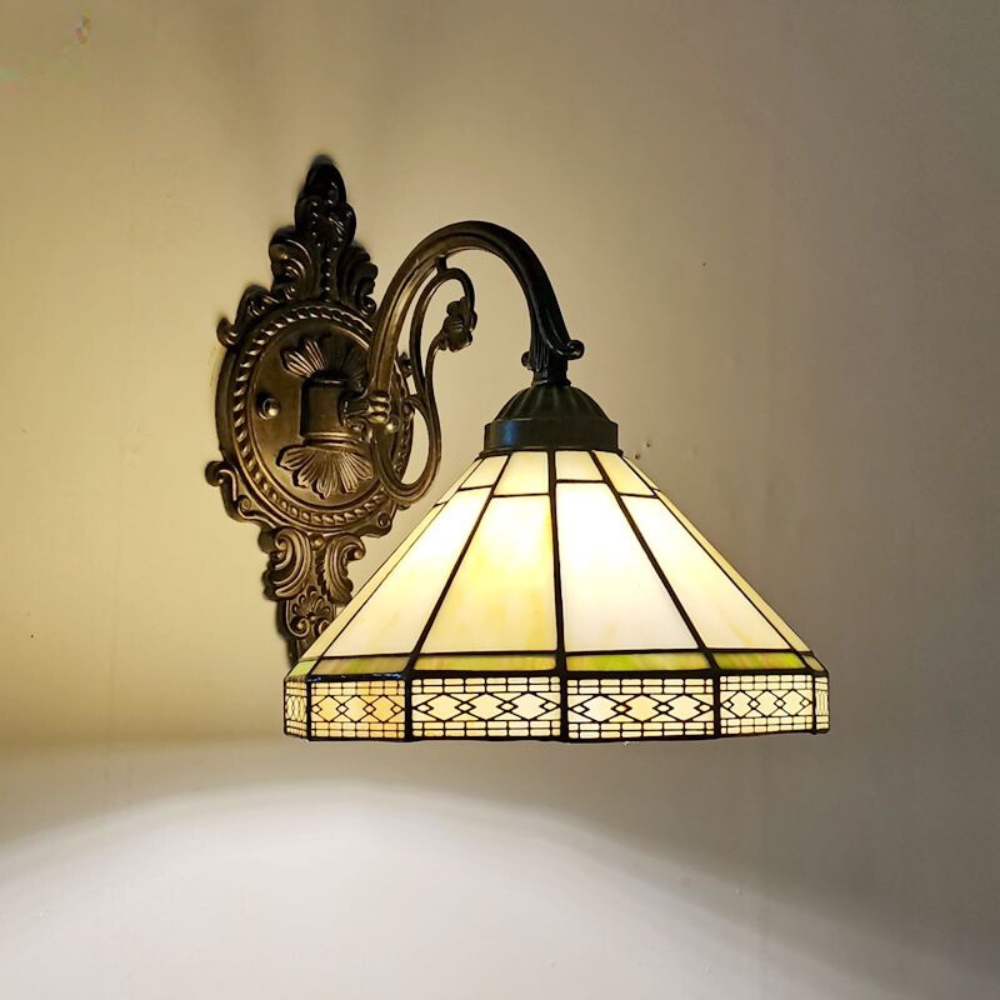Lampe champignon murale de style tiffany avec un abat-jour aux formes géométriques avec le verre jaune. L'ampoule est allumée.