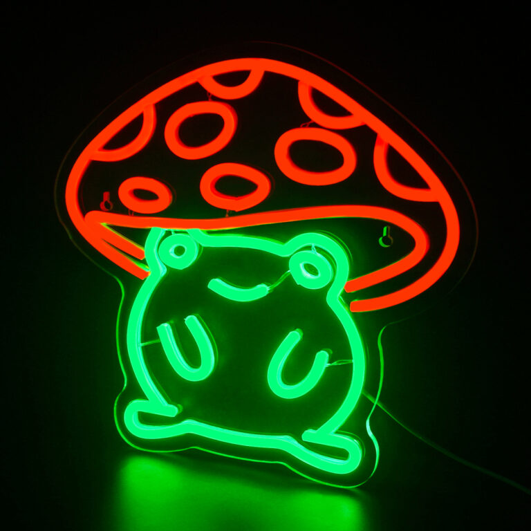 Néon en forme de champignon dont le corps vert est une grenouille et le chapeau de champignon est rouge. Sur fond noir.