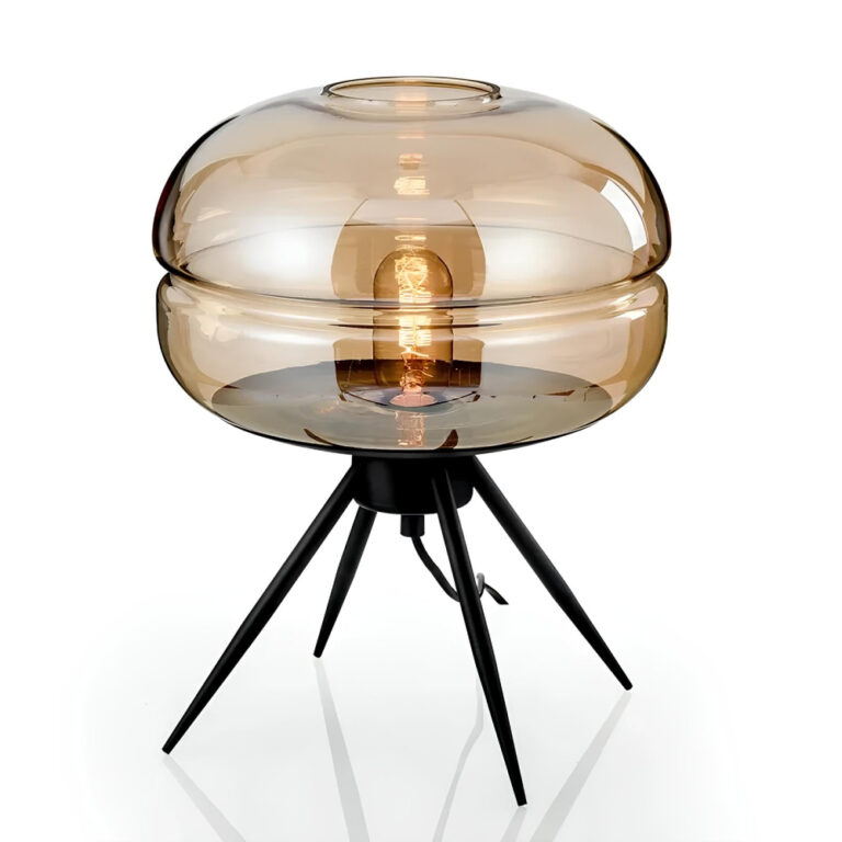 Lampe champignon en verre soufflé en teinte fumée marron. L'ampoule est allumée. Le verre est en forme d'ovale avec une rainure au centre dans l'horizontale. Le verre est maintenu par un trépied à 4 pointes noires. Sur fond blanc.